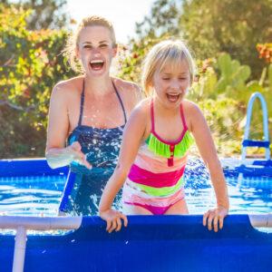 Spaß Wochenende im Freien, fröhliche gesunde Mutter und Tochter im Badeanzug spielen zusammen im Pool.