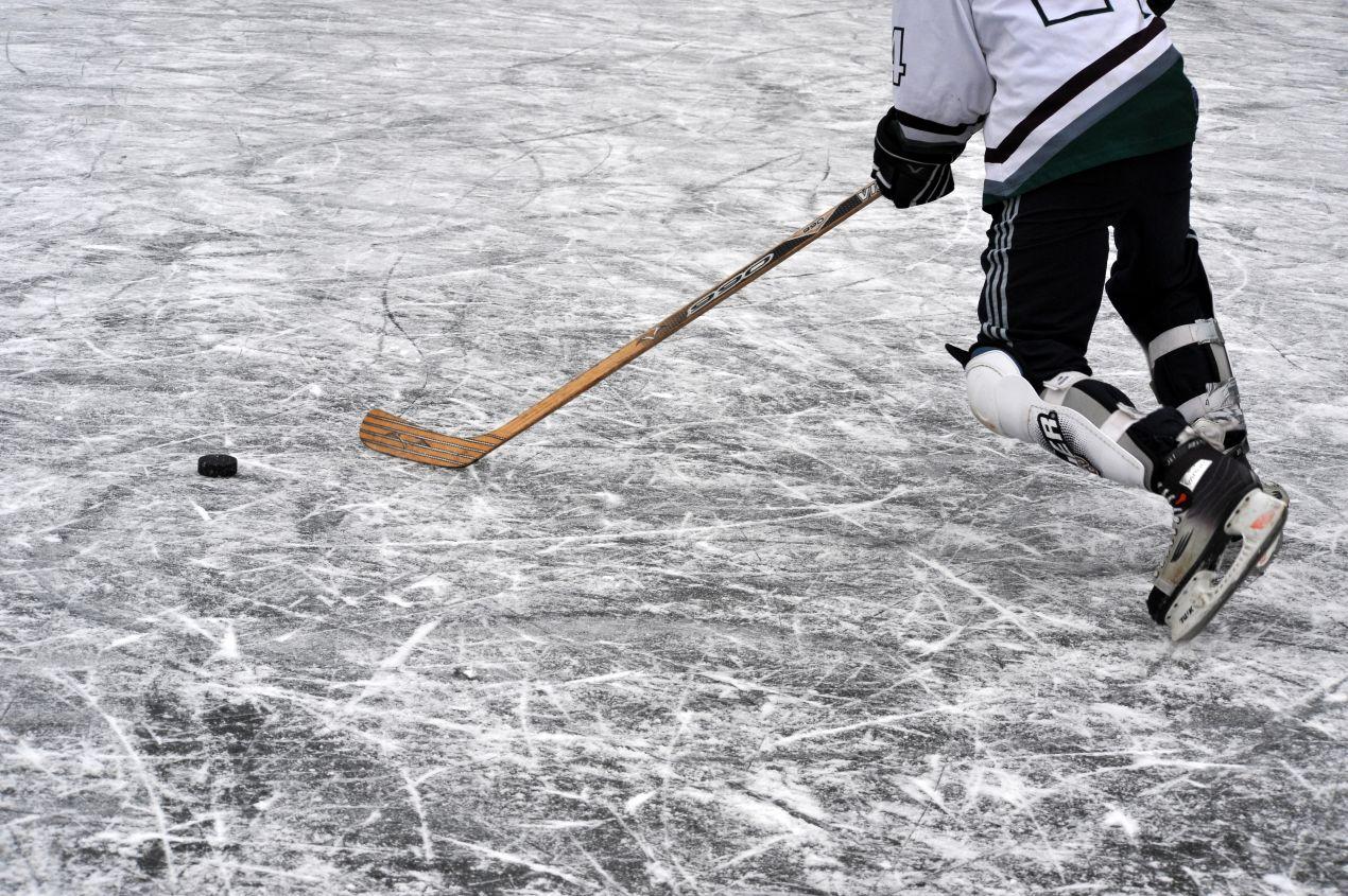 Eishockeyspieler auf dem Spielfeld in Aktion mit Schlaeger und Puck – Kufenschoner nicht im Einsatz