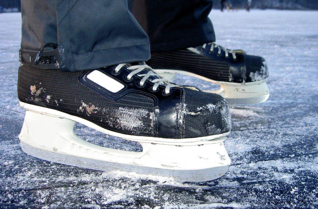 Nahaufnahme von Schlittschuhen auf dem Eis mit Schneeanhaftung – ohne Kufenschoner sichtbar
